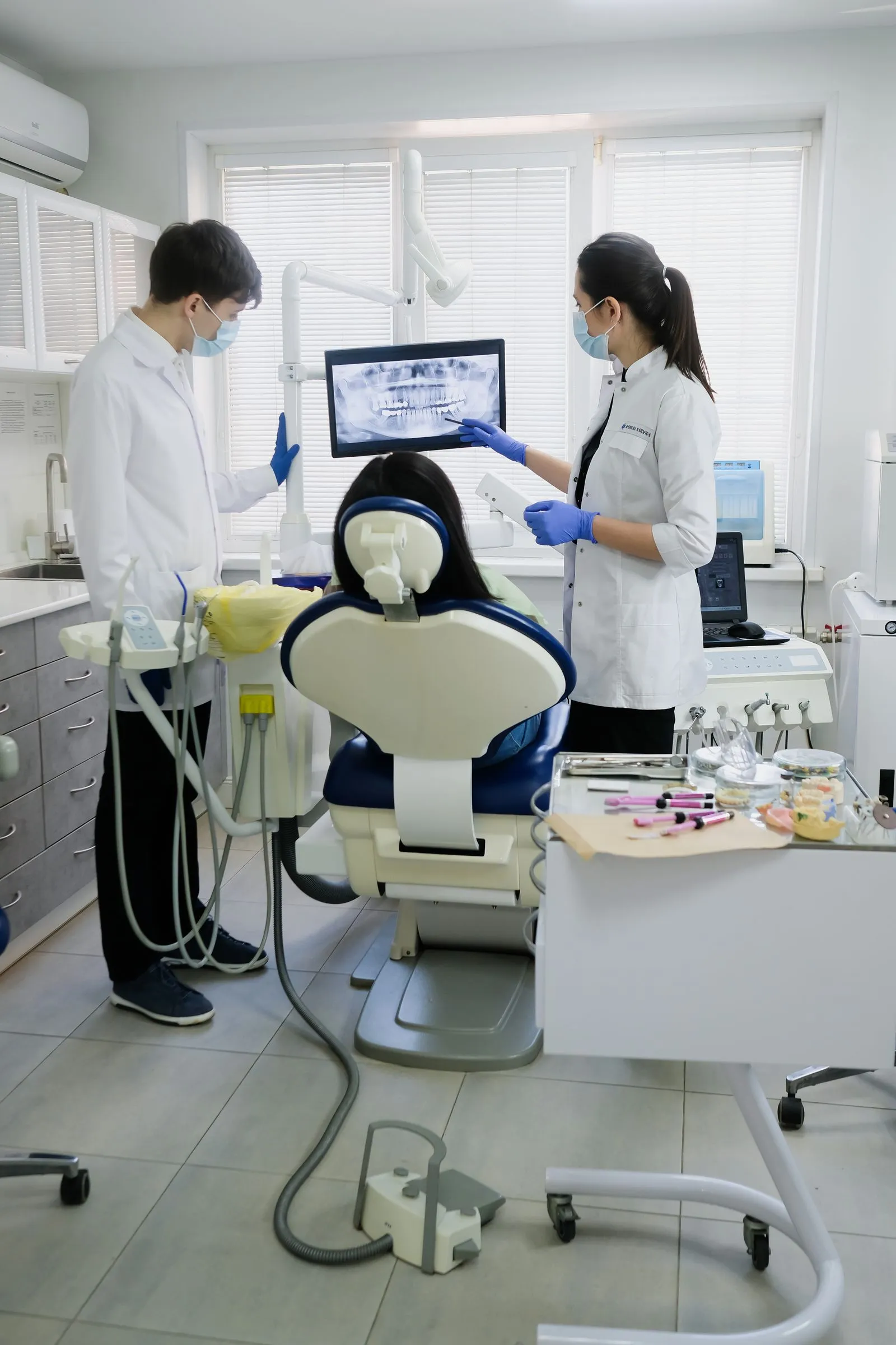 Two dentists showing a patient a panoramic X-ray on screen